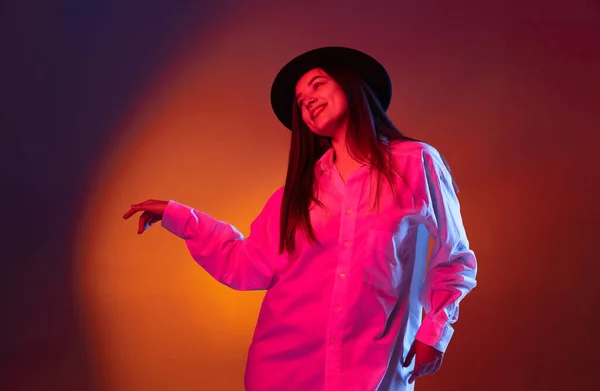 Potret gadis cantik yang tersenyum terisolasi di latar belakang studio gelap dalam cahaya neon. Konsep emosi manusia, ekspresi wajah — Stok Foto