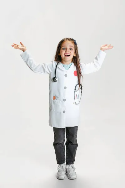 Kleuterschool mooi meisje, kind in beeld van arts dragen witte lab jas poseren geïsoleerd op witte studio achtergrond — Stockfoto