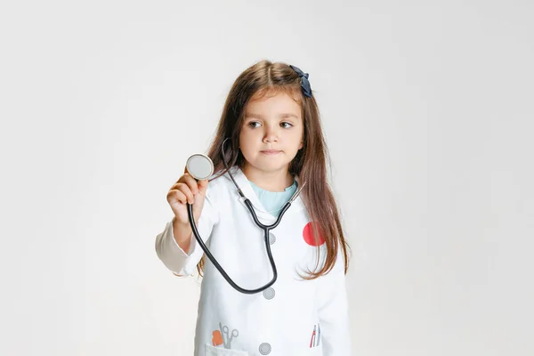 Retrato de cerca de una linda niña, niño en la imagen del médico con bata de laboratorio blanca con estetoscopio aislado en el fondo del estudio blanco — Foto de Stock