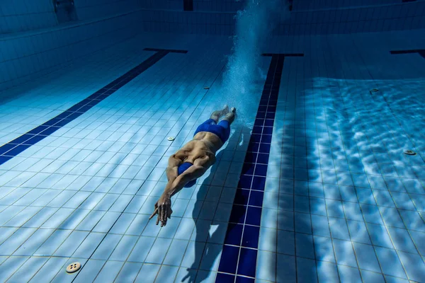 Disparos submarinos. Un nadador masculino entrenando en la piscina, adentro. Vista submarina de los movimientos de natación detalles. — Foto de Stock