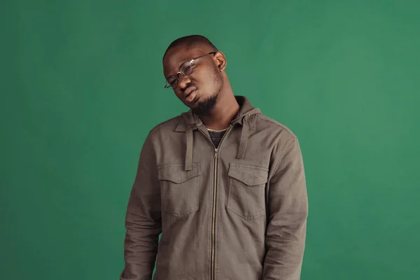 Un joven y elegante hombre africano con ropa casual aislada en el fondo del estudio de la marina. Emociones, concepto de expresión facial. —  Fotos de Stock