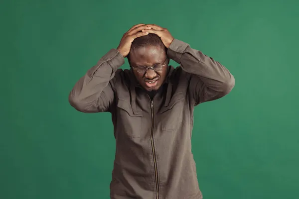 Un giovane uomo africano elegante che indossa abiti casual isolati su sfondo studio marina. Emozioni, concetto di espressione facciale. — Foto Stock