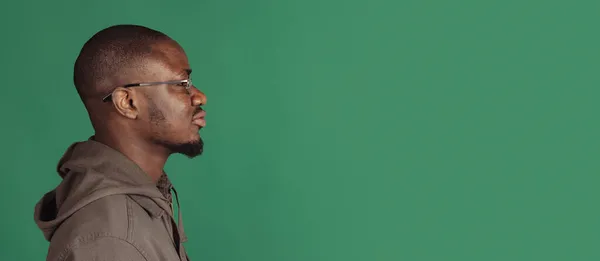 Boční pohled. Detailní záběr portrét mladého afrického muže pózujícího izolovaně na pozadí studia s copyspace pro reklamu. Oznámení — Stock fotografie