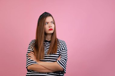 Açık pembe stüdyo arka planında duran uzun ipek saçlı güzel bir kızın portresi. Duygular ve moda kavramı