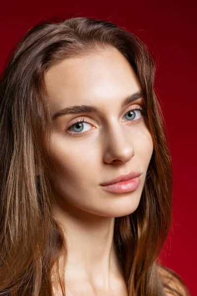 Close-up retrato de menina bonita jovem sem maquiagem isolada sobre fundo estúdio vermelho. Conceito de beleza natural. — Fotografia de Stock
