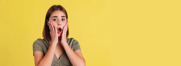 Volantino con scioccato giovane ragazza, studente in piedi con la bocca aperta e gridando isolato sul backgroud studio giallo. — Foto Stock