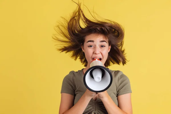 Ritratto di mezza lunghezza di giovane ragazza, studente gridando al megafono isolato sul backgroud studio giallo. — Foto Stock