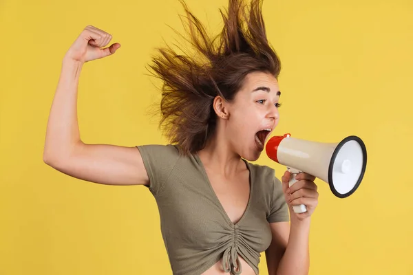 Ritratto di mezza lunghezza di giovane ragazza, studente gridando al megafono isolato sul backgroud studio giallo. — Foto Stock