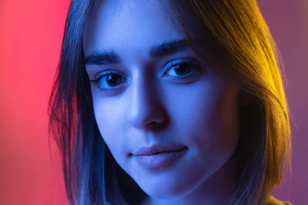 Közelkép portré fiatal aranyos lány, diák néz kamera elszigetelt rózsaszín-lila stúdió háttér neon. — Stock Fotó