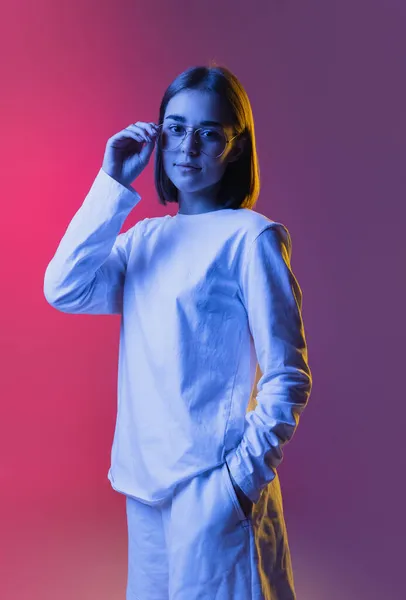 Close-up retrato de menina bonito jovem, estudante em roupas casuais ouvir música isolada no backgroud estúdio rosa-roxo em néon. — Fotografia de Stock