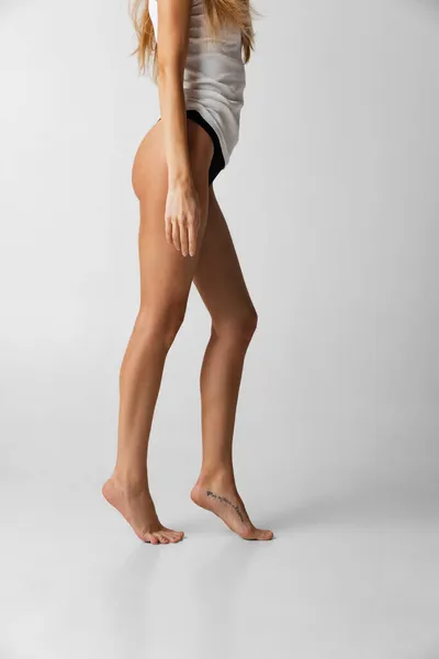 Immagine ritagliata del corpo di giovane donna magra isolata su sfondo grigio studio. Concetto di bellezza naturale. Vista laterale — Foto Stock