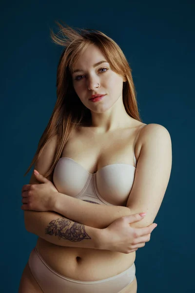 Portrait de jeune belle femme rousse en tenue intérieure posant isolée sur fond de studio bleu. Concept de beauté naturelle. — Photo