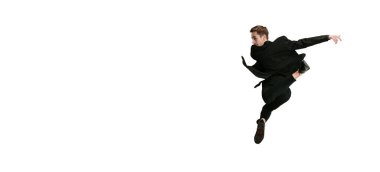 Siyah takım elbiseli genç bir dansçının beyaz arka planda izole bir şekilde atlaması. Sanat, hareket, eylem, esneklik, ilham kavramı.