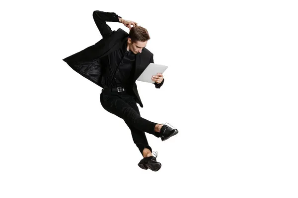 Young man in black business suit using tablet isolated on white background. Art, motion, action, flexibility, inspiration concept. — Stock Photo, Image