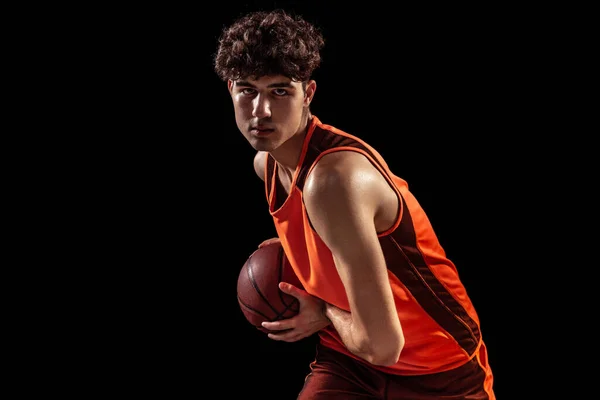 Retrato de primer plano del jugador de baloncesto posando con pelota aislada sobre fondo oscuro del estudio. Deporte, energía, potencia, resultados. — Foto de Stock