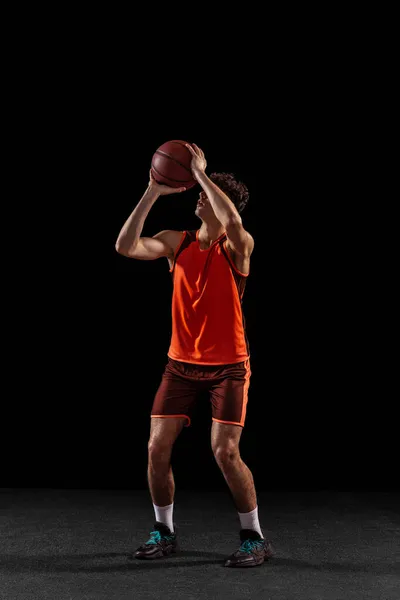 검은 스튜디오 배경에서 분리 된 농구 선수 훈련의 전체 길 이 초상화. 공을 타고 달리는 키큰 근육질 운동 선수. — 스톡 사진