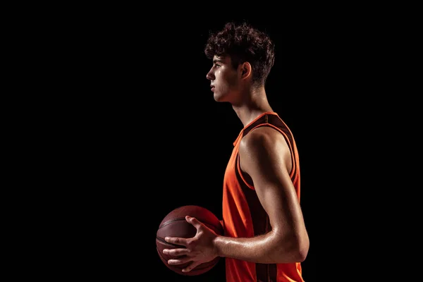 농구 선수가 어두운 스튜디오 배경에서 고립된 공을 가지고 포즈를 취하는 것에 대한 개요. 스포츠, 에너지, 힘, 결과. — 스톡 사진