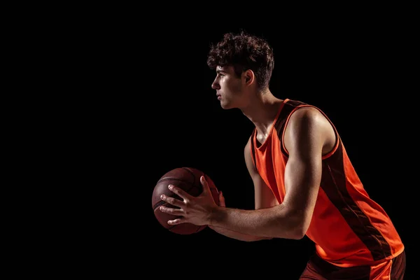 在黑漆漆的工作室背景下,篮球运动员与球隔离在一起摆姿势的轮廓视图.体育、能源、力量、成果. — 图库照片