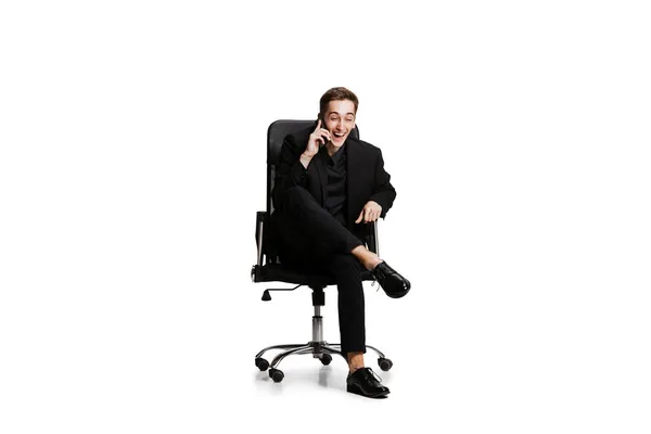 Retrato de homem jovem em terno de negócios preto, gerente de escritório sentado na cadeira isolada no fundo branco. Arte, conceito de inspiração. — Fotografia de Stock