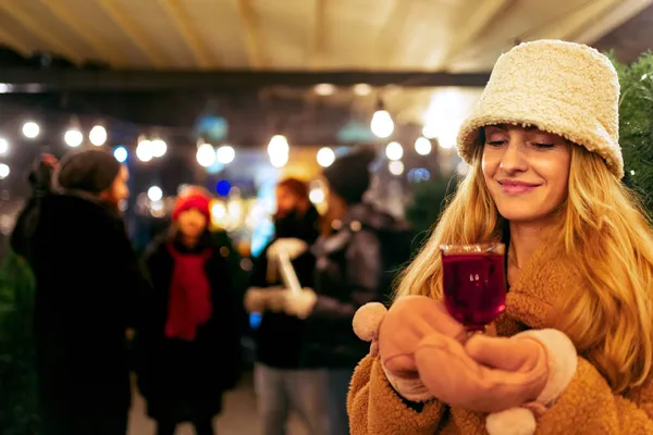 겨울 옷을 입고 섹시 한 음료를 마시고 꿈을 꾸는 아름다운 소녀의 근접 사진. 겨울 시장에서 친구들 과 함께 저녁 시간을 보내는 모습. — 스톡 사진