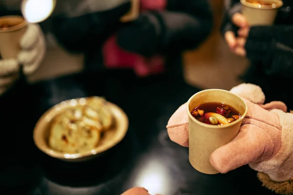 Close-up mensenhanden in de winter wanten met hete kop warme glühwein met specerijen. Vakantie, tradities, Kerstmarkt, Kerstconcept — Stockfoto