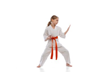 Küçük bir kızın stüdyo çekimi, beyaz arka planda yalnız başına karate eğitimi. Spor, eğitim, beceri kavramı
