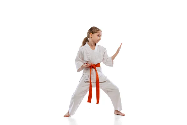 Studioaufnahme eines kleinen Mädchens, das allein auf weißem Hintergrund Karate trainiert. Konzept von Sport, Bildung, Fertigkeiten — Stockfoto