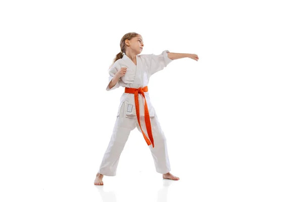 Одна маленькая девочка, карате в кимоно, практикуется на белом фоне. Спорт, образование, навыки — стоковое фото