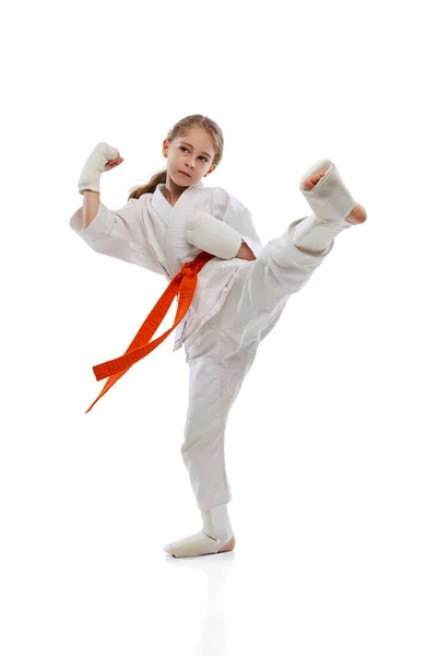 Studio skott av liten flicka, ung karate utbildning ensam isolerad över vit bakgrund. Begreppet idrott, utbildning, färdigheter — Stockfoto
