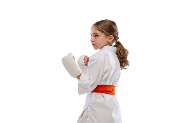 En liten flicka, ung karate i kimono övar isolerad över vit bakgrund. Begreppet idrott, utbildning, färdigheter — Stockfoto