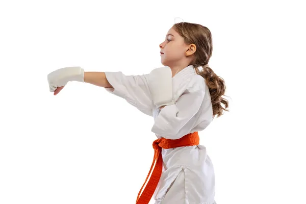 Ένα μικρό κορίτσι, νεαρό καράτε στο κιμονό να προπονείται απομονωμένο σε λευκό φόντο. Έννοια του αθλητισμού, της εκπαίδευσης, των δεξιοτήτων — Φωτογραφία Αρχείου