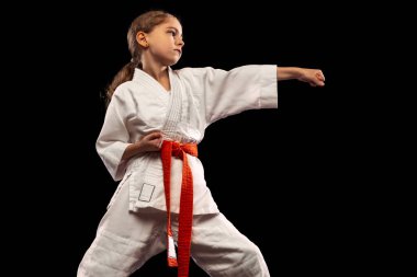 Küçük bir kız, kimonolu genç bir karateci karanlık arka planda izole edilmiş. Spor, eğitim, beceri kavramı