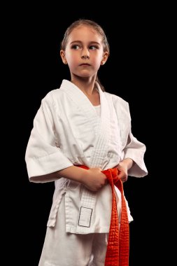 Küçük, sportif bir kızın yarım boy portresi. Karanlık arka planda izole edilmiş bir kadın karatesi. Spor, eğitim, beceri kavramı