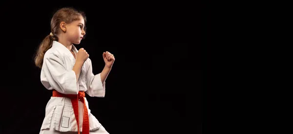 Uma menina, jovem karaté em posição de luta isolada sobre fundo escuro. Conceito de esporte, educação, habilidades — Fotografia de Stock