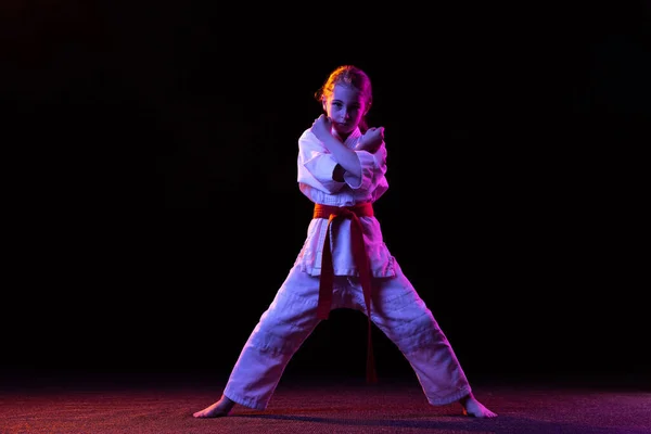 Karate, taekwondo meisje met gele riem geïsoleerd op donkere achtergrond in neon licht. Begrip sport, onderwijs, vaardigheden — Stockfoto