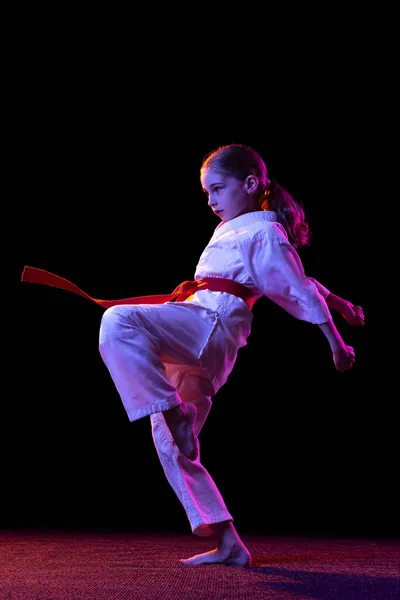Karate, taekwondo meisje met gele riem geïsoleerd op donkere achtergrond in neon licht. Begrip sport, onderwijs, vaardigheden — Stockfoto