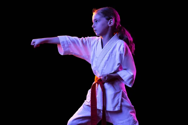 暗い背景の上に隔離された練習着物の若い空手の1人の少女。スポーツ、教育、スキルの概念 — ストック写真