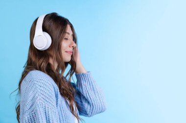 Müziği dinleyen genç güzel bir kızın yarım boy portresi. Donanma renginde stüdyo arka planında neon ışıklarıyla izole edilmiş..