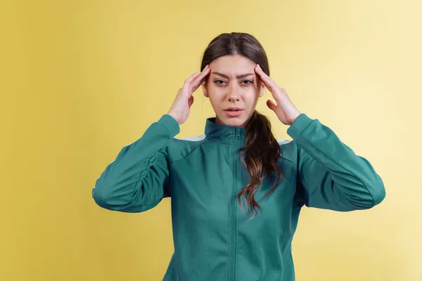 Retrato de menina irritada jovem em traje verde posando isolado no fundo do estúdio amarelo em luz de néon. Emoções, expressão facial — Fotografia de Stock