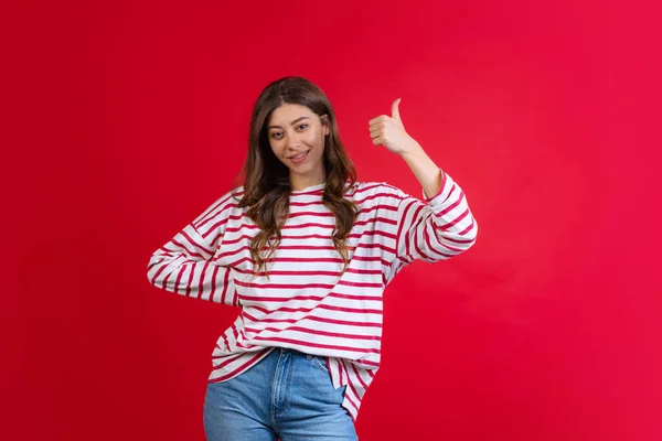 Emotionale junge schöne Mädchen in Pullover und Jeans posieren isoliert auf rotem Studiohintergrund. Konzept der Emotionen, Mimik — Stockfoto