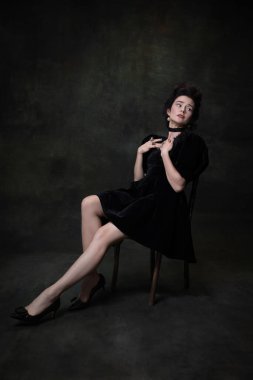 Klasik ortaçağ kraliyet mensubu siyah elbiseli, koyu renkli arka planda izole edilmiş genç ve tapılası bir kadının portresi..