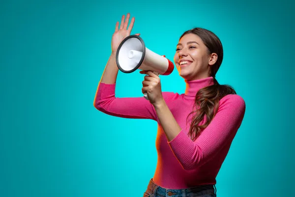 Retrato de jovem bela menina emocional gritando em megafone isolado na cor da marinha estúdio fundo em luz de néon. — Fotografia de Stock