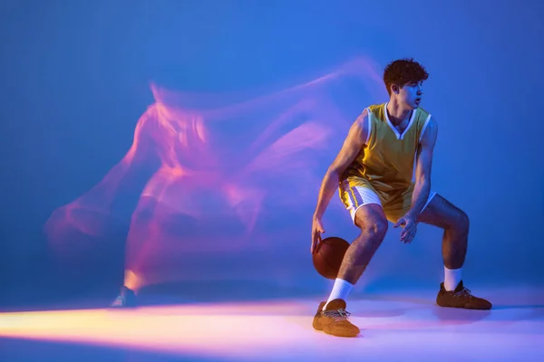 Retrato de larga duración de entrenamiento profesional de jugador de baloncesto con pelota aislada sobre fondo de estudio azul en luz de neón mixta. —  Fotos de Stock