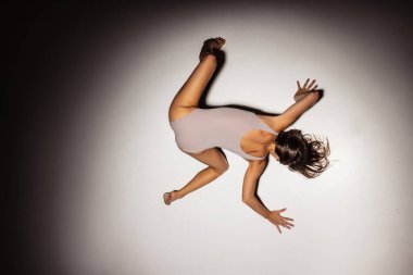 Yüksek açılı genç, esnek, zarif kız, sanat performansında kadın dansçı, sahne ışıkları altında, karanlık stüdyoda izole edilmiş..