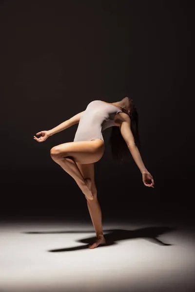 Dynamiskt porträtt av unga flexibla samtida dansare dans isolerad på mörk studio bakgrund i rampljuset. Konst, skönhet, inspiration koncept. — Stockfoto