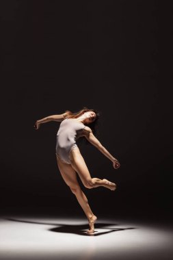 Karanlık stüdyonun arka planında izole edilmiş genç, esnek, düşünceli dansçının dinamik portresi. Sanat, güzellik, ilham konsepti.