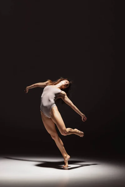 Dynamisch portret van jonge flexibele contemp danser dansen geïsoleerd op donkere studio-achtergrond in de schijnwerpers. Kunst, schoonheid, inspiratie concept. — Stockfoto