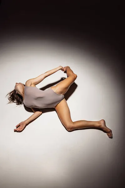 Vista de alto ângulo de jovem flexível, menina graciosa, dançarina de desprezo feminino em performance de arte isolada no fundo escuro estúdio em destaque. — Fotografia de Stock