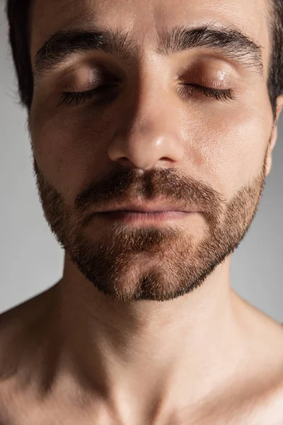 Großaufnahme des Gesichts eines jungen gutaussehenden bärtigen Mannes ohne Hemd mit geschlossenen Augen, isoliert auf grauem Studiohintergrund. Natürliche Schönheit — Stockfoto