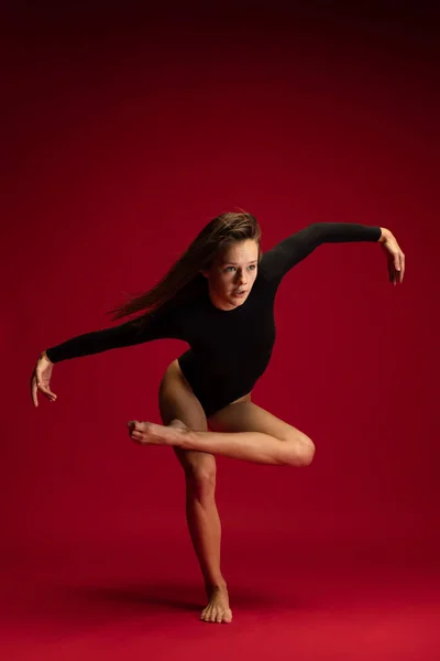 作为一个情绪化的、灵活的年轻相思舞蹈演员，芭蕾舞演员在深红色背景下跳得孤立无援。艺术、美、灵感概念. — 图库照片